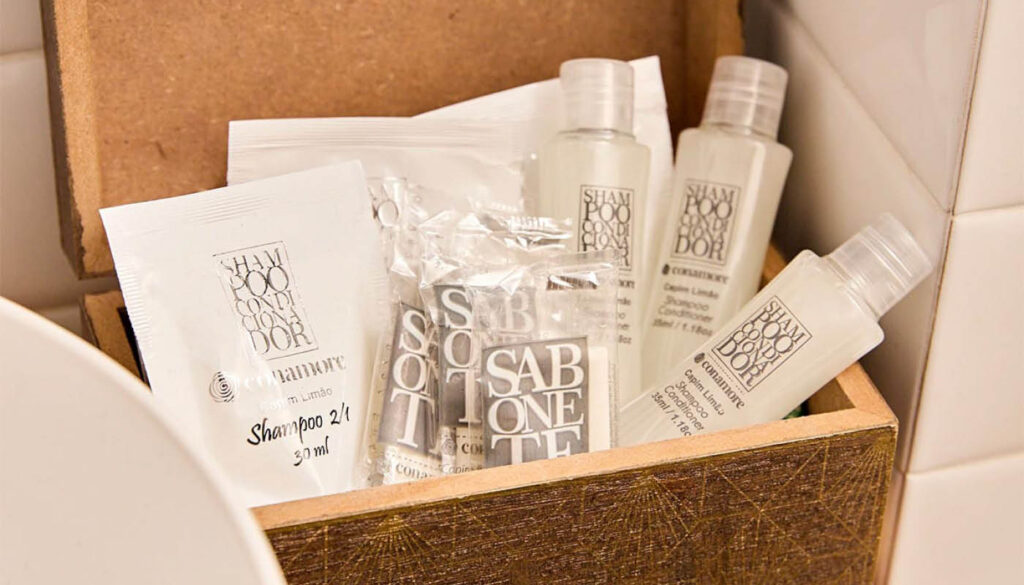 Produtos de amenities Conamore em caixa de madeira, com shampoo, condicionador e sabonetes nos aromas Capim Limão e Herbal.