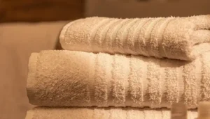Toalhas brancas de hotel dobradas, com textura macia e alta absorção para hotelaria e hospedagem