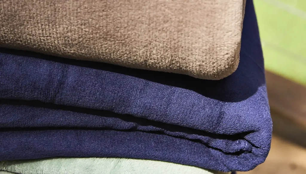 Cobertores de microfibra dobrados em hotel destacando conforto e praticidade na hotelaria